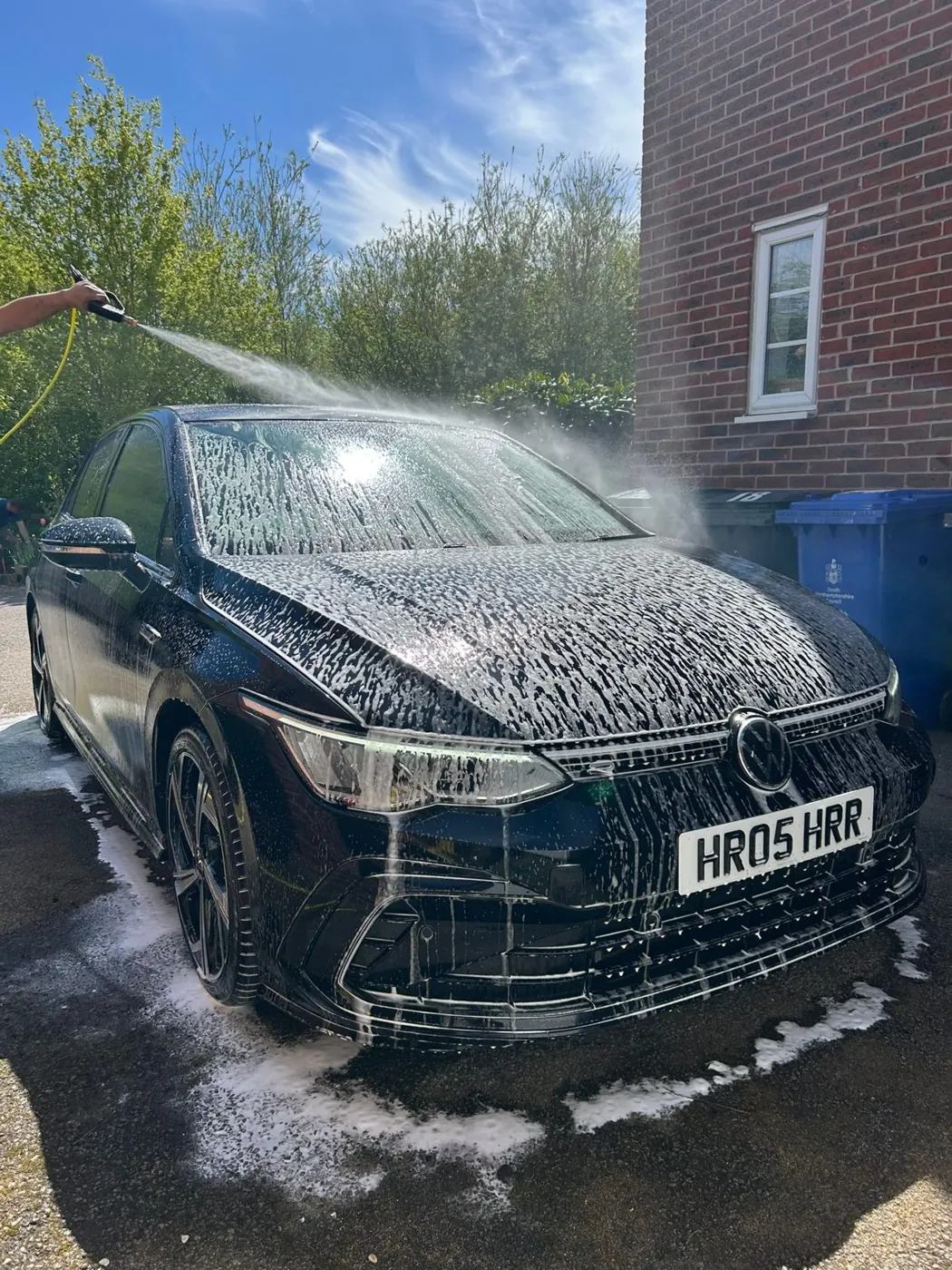 Black Volkswagen Golf being rinsed after a snow-foam pre-wash during an Exterior Refresh