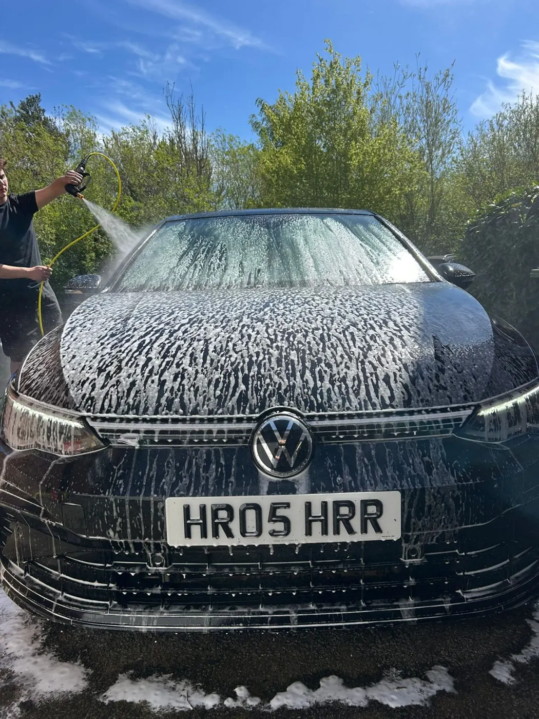 Thick snow foam covering the front of a black hatchback