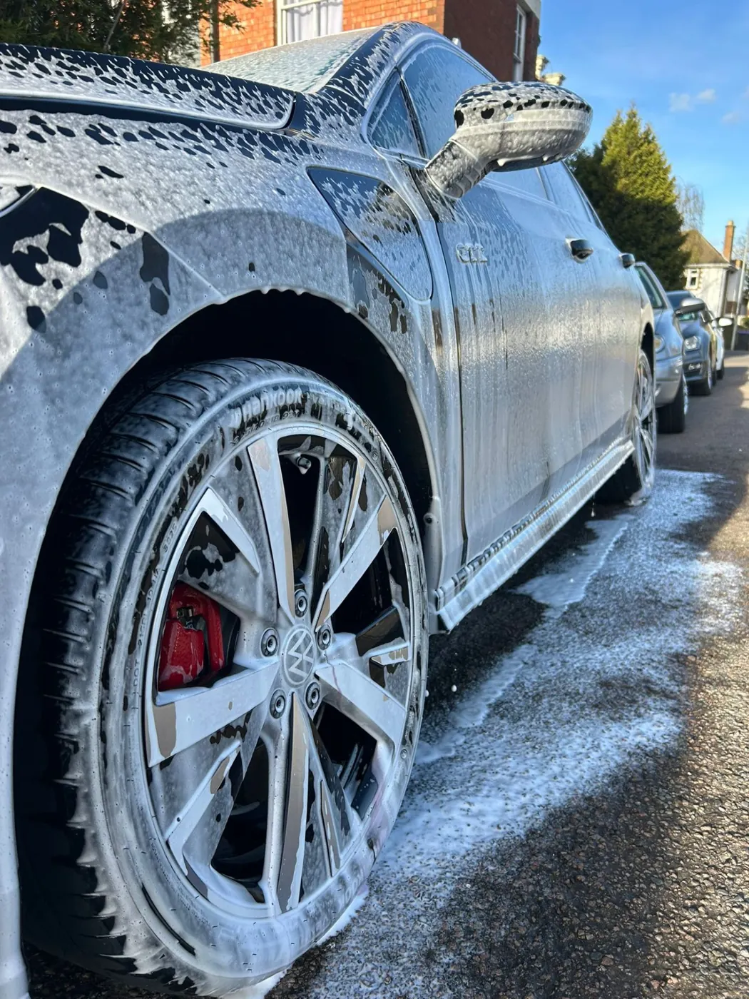 Alloy wheel and red brake caliper under snow foam